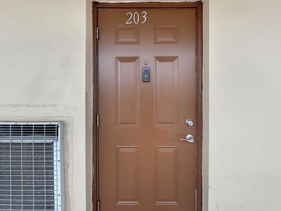 Front view of a door labeled '203' on a building exterior.