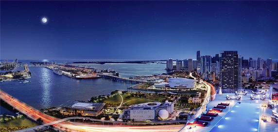 Panoramic view of a cityscape with illuminated buildings, a river, and a bridge at night.