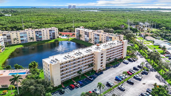Aerial view of an apartment complex with a lake and water fountain.