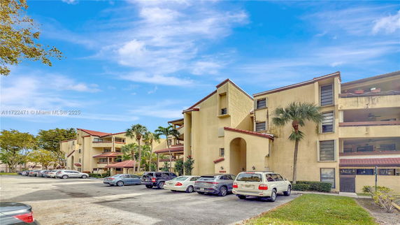 Front view of a multi-story residential building with balconies and parking area.