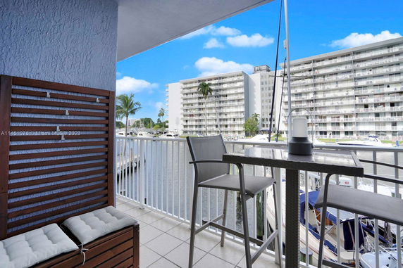 Balcony view overlooking a marina with tall residential buildings and boats.