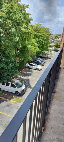 Elevated view of an outdoor parking area with several cars and trees.