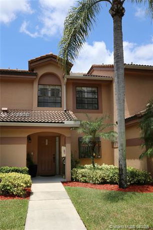 Front view of a two-story house with a tiled roof and an arched entryway.