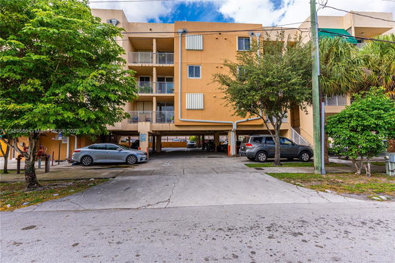 Outdoor view of a multi-story building with a parking area in front.