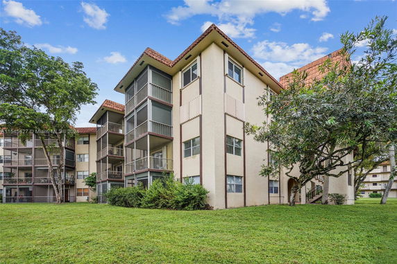 Front view of a multi-story residential building with balconies and a red-tiled roof.