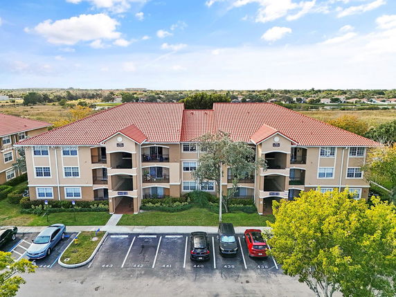 Front view of a multi-story apartment building with a red tile roof and beige exterior.