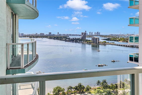 Wide angle view from a balcony overlooking a body of water with city buildings in the distance.