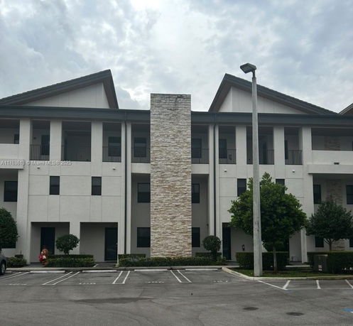 Front view of a multi-story building with a stone accent wall and parking area.