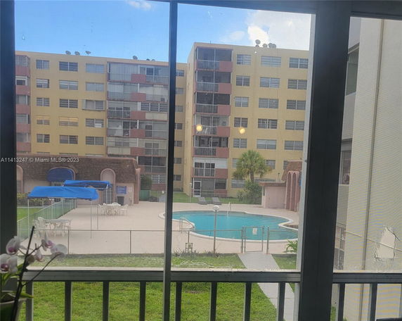 View of a swimming pool area surrounded by multi-story apartment buildings.