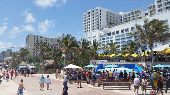 View of a beachfront area with a large hotel building and palm trees.