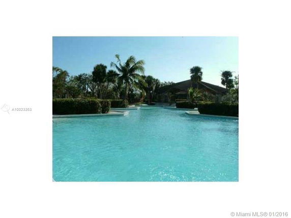 Large outdoor swimming pool with surrounding greenery and palm trees.