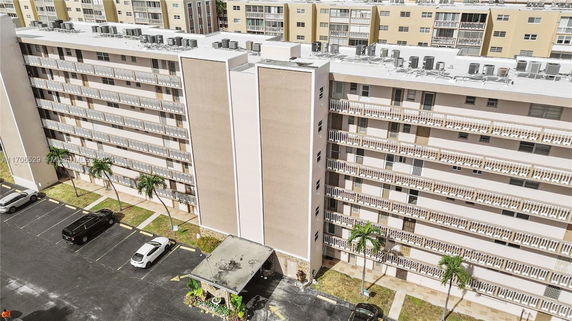 Front view of a multi-story apartment building with balconies and parking area.