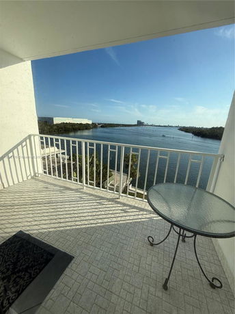 Panoramic view of a water body from a balcony with white railings and a round glass table.