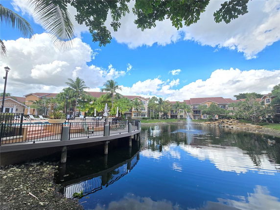 Scenic view of buildings with a deck area overlooking a pond and fountain.