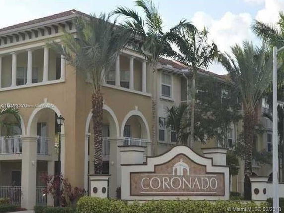 Front view of a multi-story building with arched balconies and a sign marked 'CORONADO'.