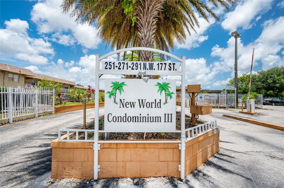Sign for New World Condominium III with buildings in the background.