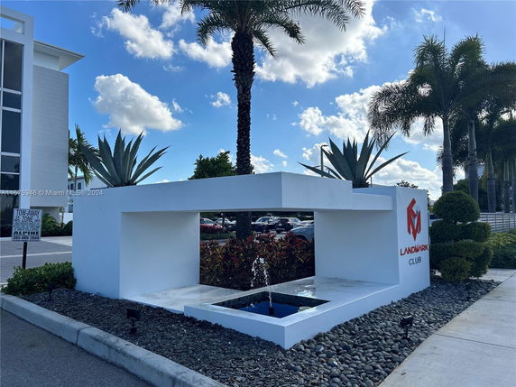 Front view of a modern building with a decorative sign and landscaped area.