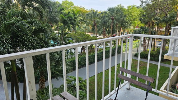 View from a balcony overlooking greenery and a walkway.