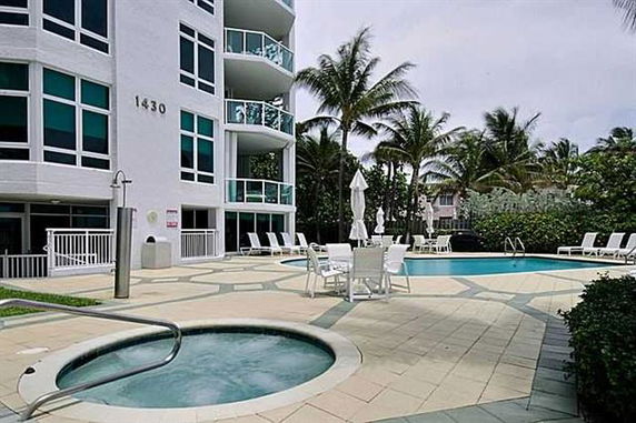 View of a multi-story building with a pool and patio area.