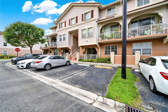 Outdoor view of a residential building with parked cars in front.