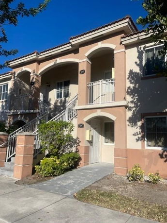 Front view of a two-story house with arched entryways and a small balcony.