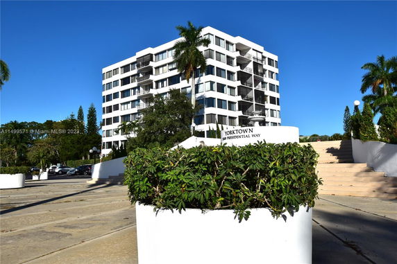 Front view of a multi-story residential building with white exterior and balconies.