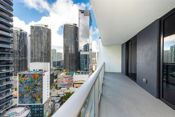 View of cityscape from a balcony with surrounding high-rise buildings.