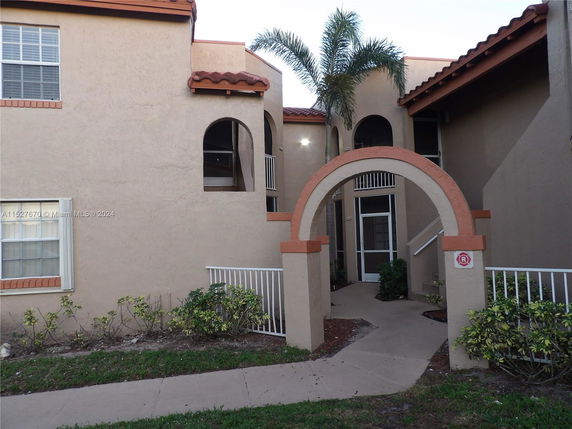 Front view of a two-story building with an archway entrance and a tiled roof.