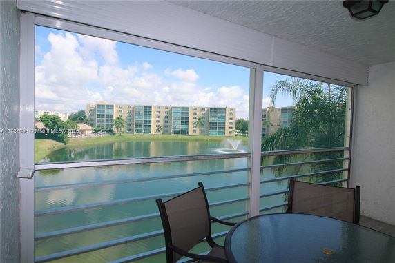 View from a balcony overlooking a pond and apartment buildings with a fountain.