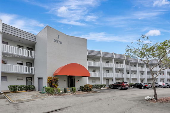 Front view of a multi-story residential building with balconies and an orange entrance canopy.