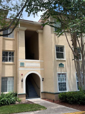 Front view of a multi-story residential building with an entrance arch and staircase.
