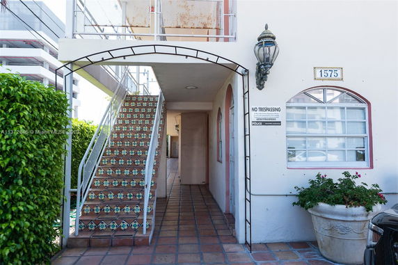 Front view of a building entrance with decorative tile stairs and archway.