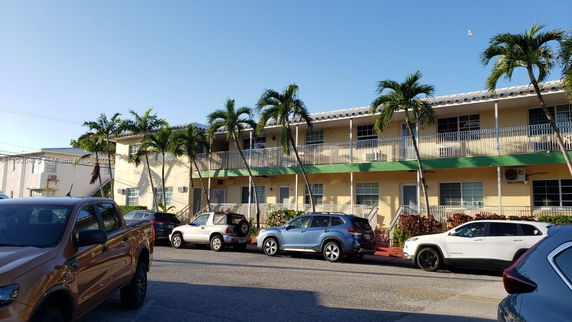 Front view of a two-story building with palm trees in front.