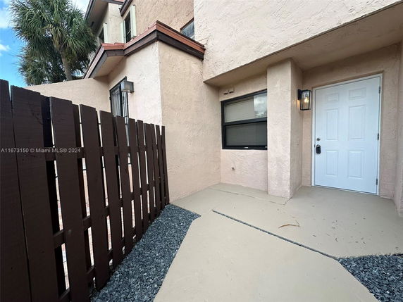 Front view of a two-story house with a fenced entrance and white door.