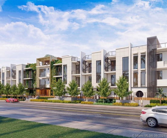 Front view of a modern multi-story residential building with greenery and spiral staircases.