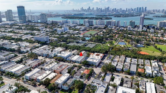 Aerial panoramic view of a cityscape with buildings, streets, and water in the background.
