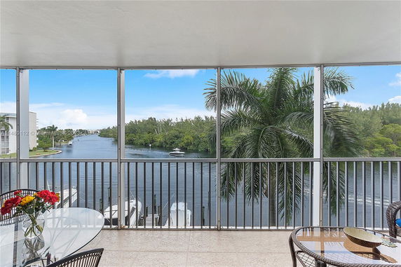 Balcony view overlooking a river with trees and boats.