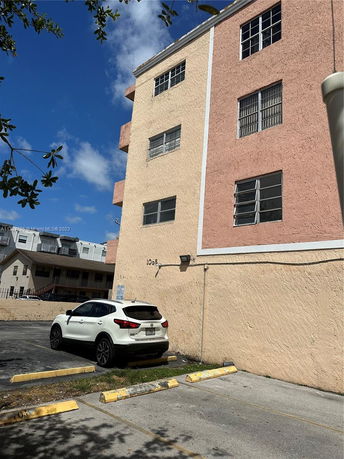 Exterior view of a multi-story building with parking area.