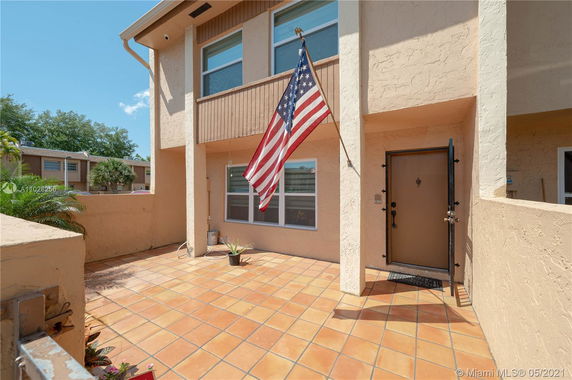 Front view of a two-story house with a tiled courtyard and an American flag.