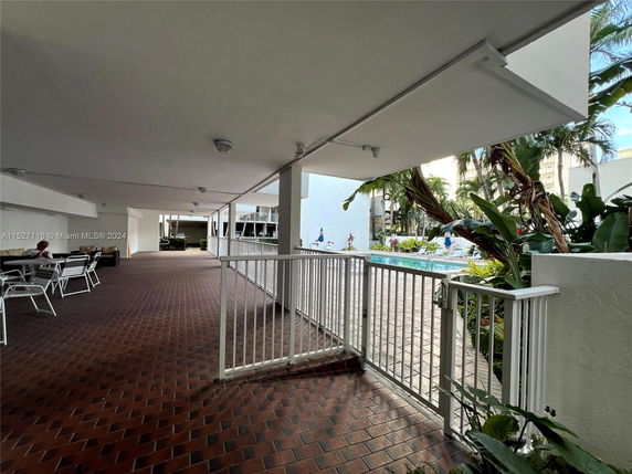 View of an outdoor area with seating and a swimming pool surrounded by lush greenery.