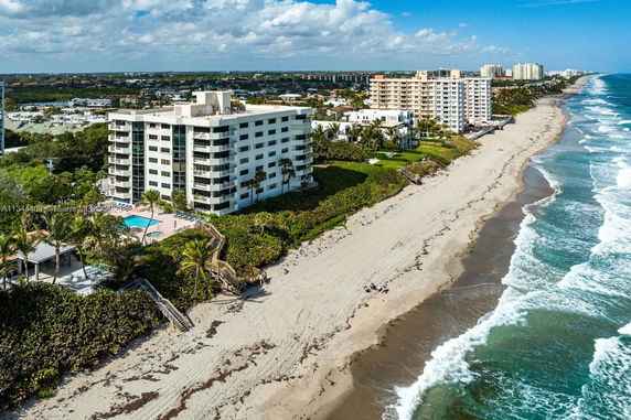 Aerial view of beachfront apartments adjacent to a sandy beach and ocean.