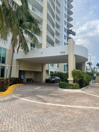 Front view of a high-rise building with balconies and entrance driveway.