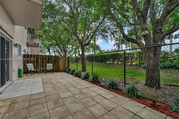 Outdoor patio area with chairs and fencing, view of trees and grass beyond.