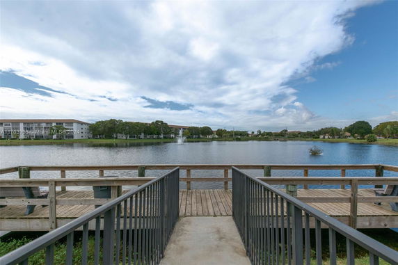 View of lake with surrounding buildings and a wooden deck in the foreground.