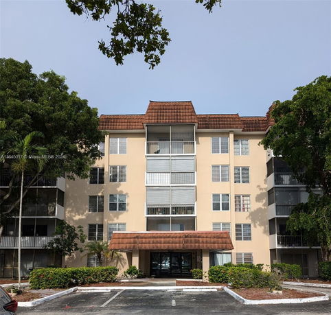 Front view of a multi-story apartment building with balconies and an entrance canopy.