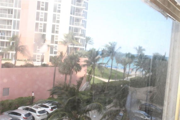 View from a building overlooking a nearby high-rise with a beach in the background.
