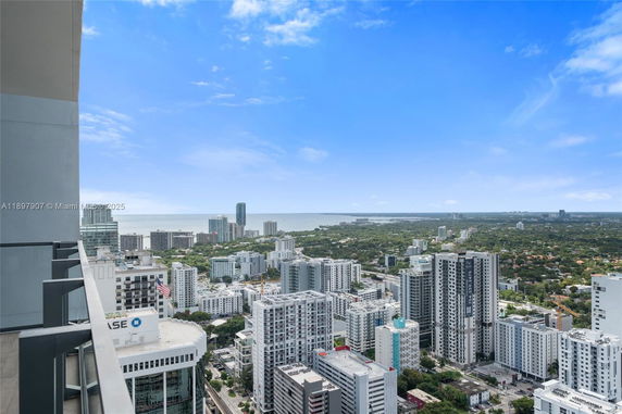 Panoramic view of a cityscape with high-rise buildings and distant sea.