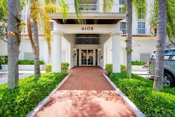 Front view of a building entrance with white columns and tiled walkway.