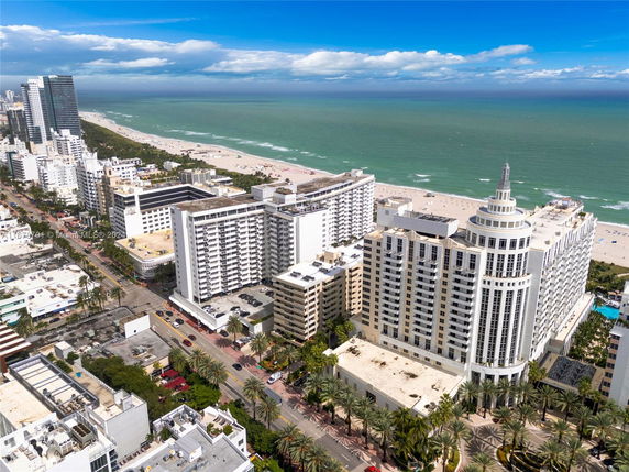Aerial view of beachfront high-rise buildings with a sandy beach and ocean in the background.