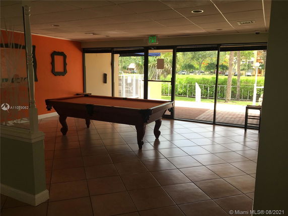 Room with a billiards table and large glass doors in a recreational area.